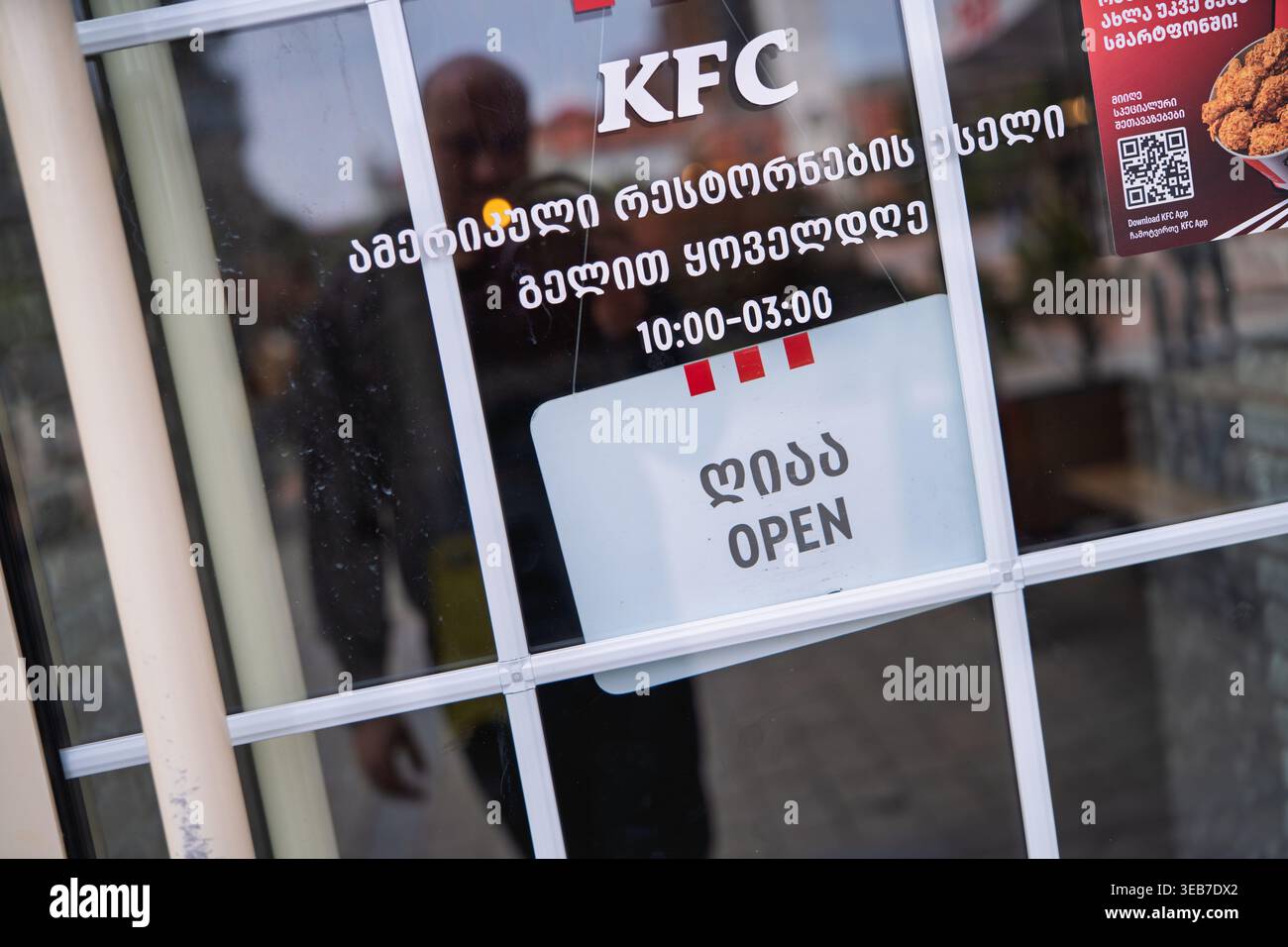 Batumi, georgia 21. april 2026: kfc-Schaufensterfenster in batumi mit zweisprachigem geöffnetem Schild und Öffnungszeiten auf georgisch und englisch, städtische Straße r Stockfoto