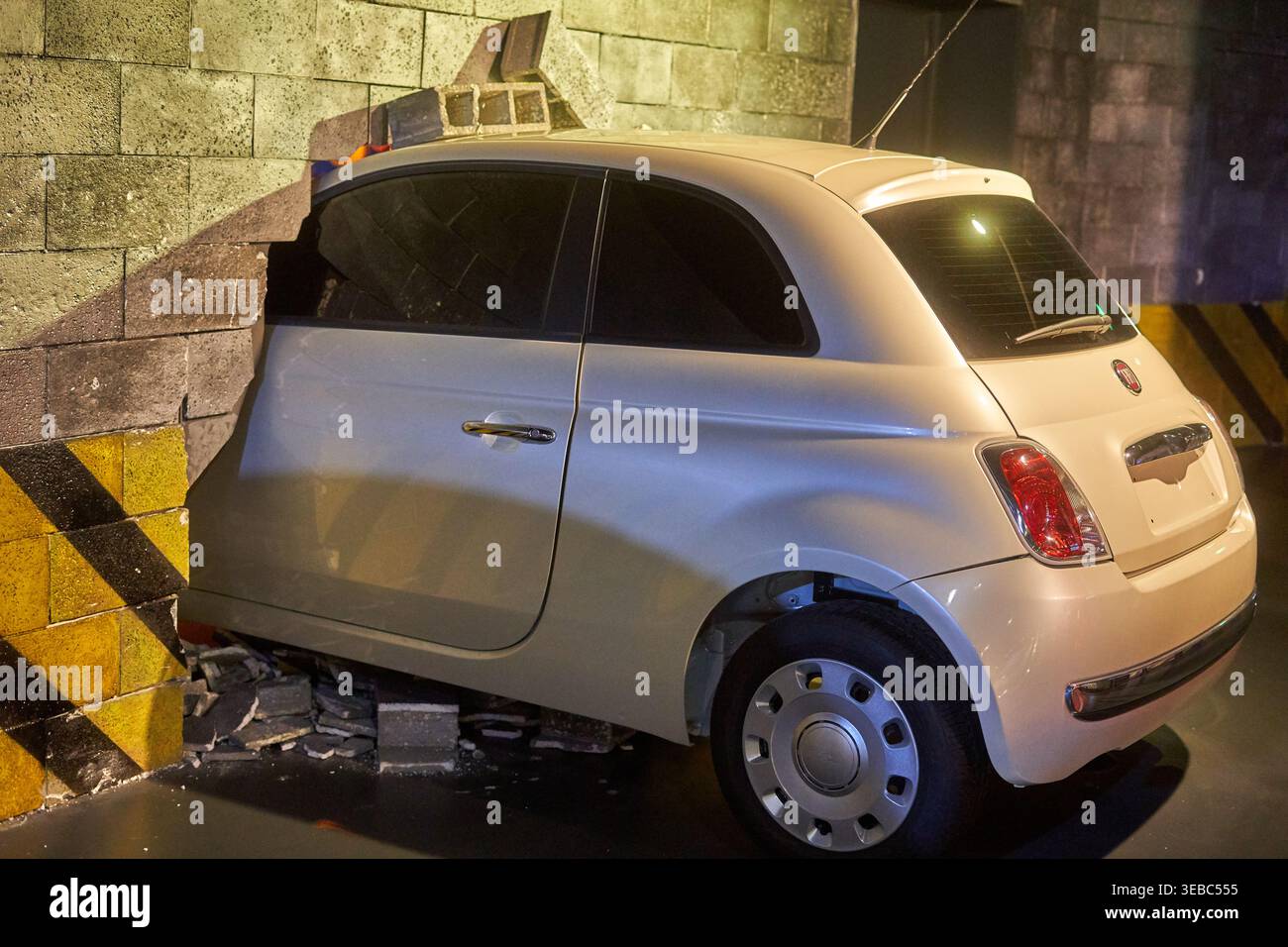 Ein weißer Fiat 500 prallte gegen eine Betonmauer in einer Art unterirdischer Parkgarage oder Tunnel. Der vordere Teil des Stockfoto