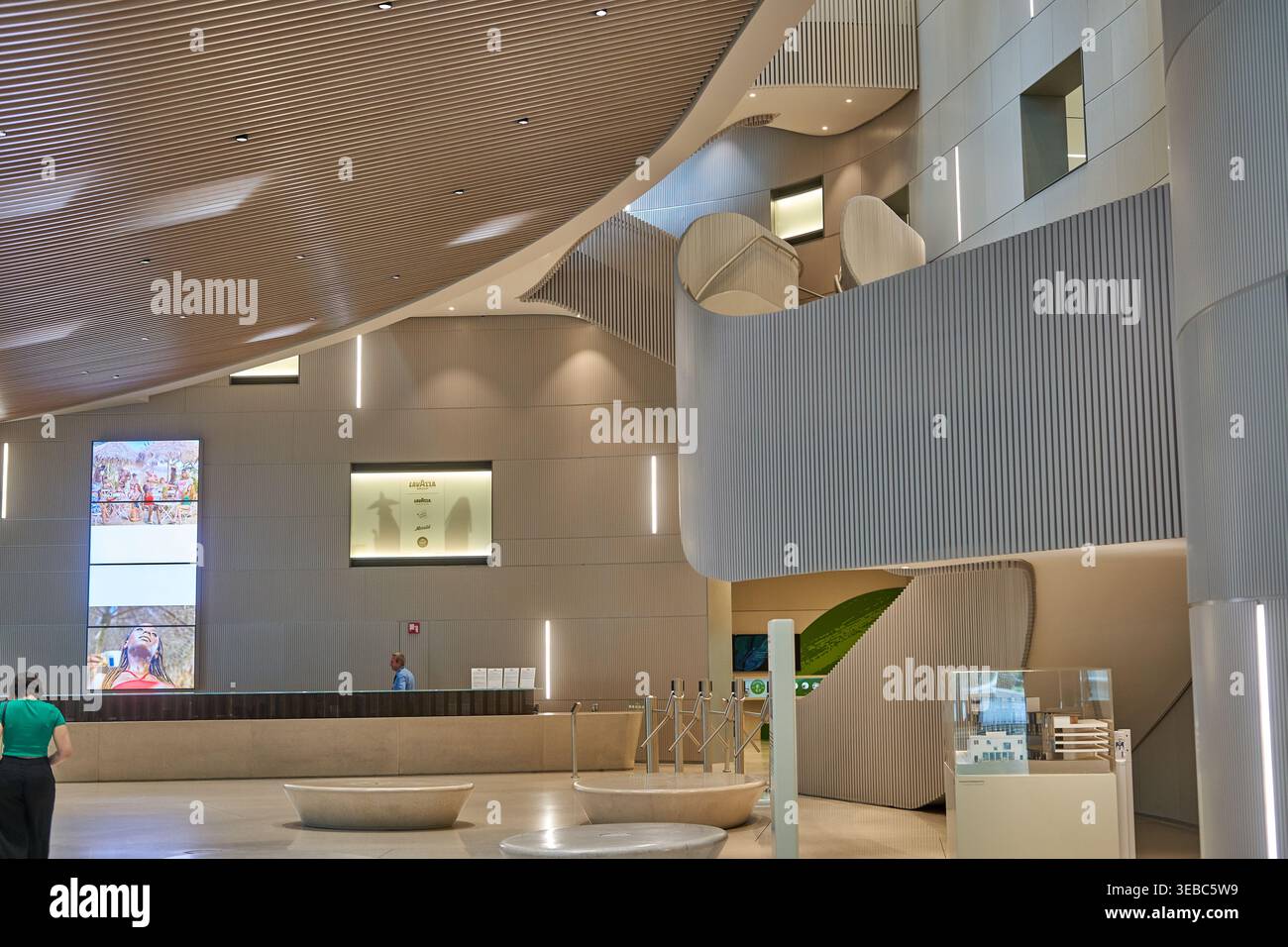 Moderne Innenlobby eines zeitgenössischen Kulturgebäudes oder Museums mit geschwungenen architektonischen Elementen, Holzlatten-Decke und Minimalismus Stockfoto
