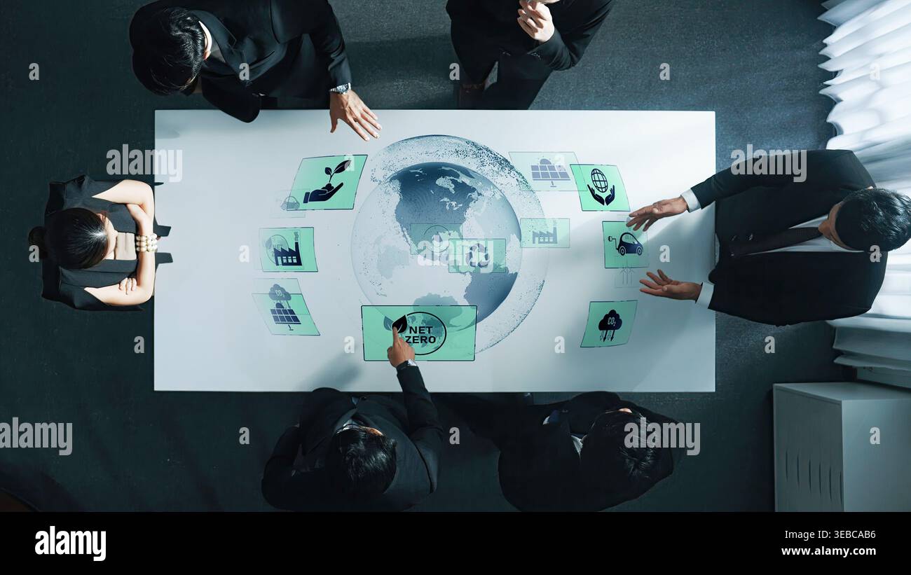 In einem modernen Büro arbeitet eine Gruppe von Fachleuten zusammen, die Nachhaltigkeitsziele diskutieren und gleichzeitig mit digitalen Grafiken auf der ganzen Welt interagieren Stockfoto