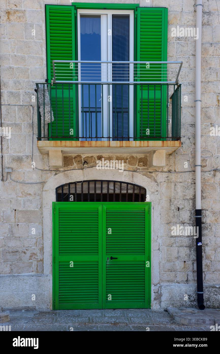 Traditionelle Steinhausfassade mit hellgrünen Fensterläden, Balkon und Holztür in der historischen mediterranen Stadt Stockfoto
