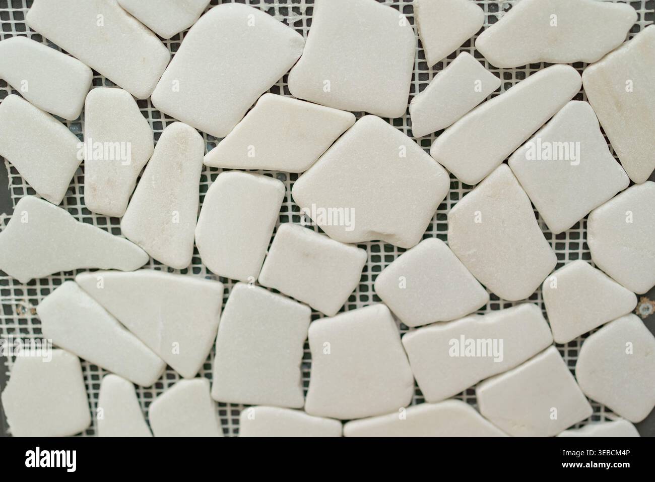 Nahaufnahme größerer glatter weißer Steinfliesen im Mosaikstil. Saubere, elegante Textur, geeignet für moderne Innenräume und Architektur Stockfoto
