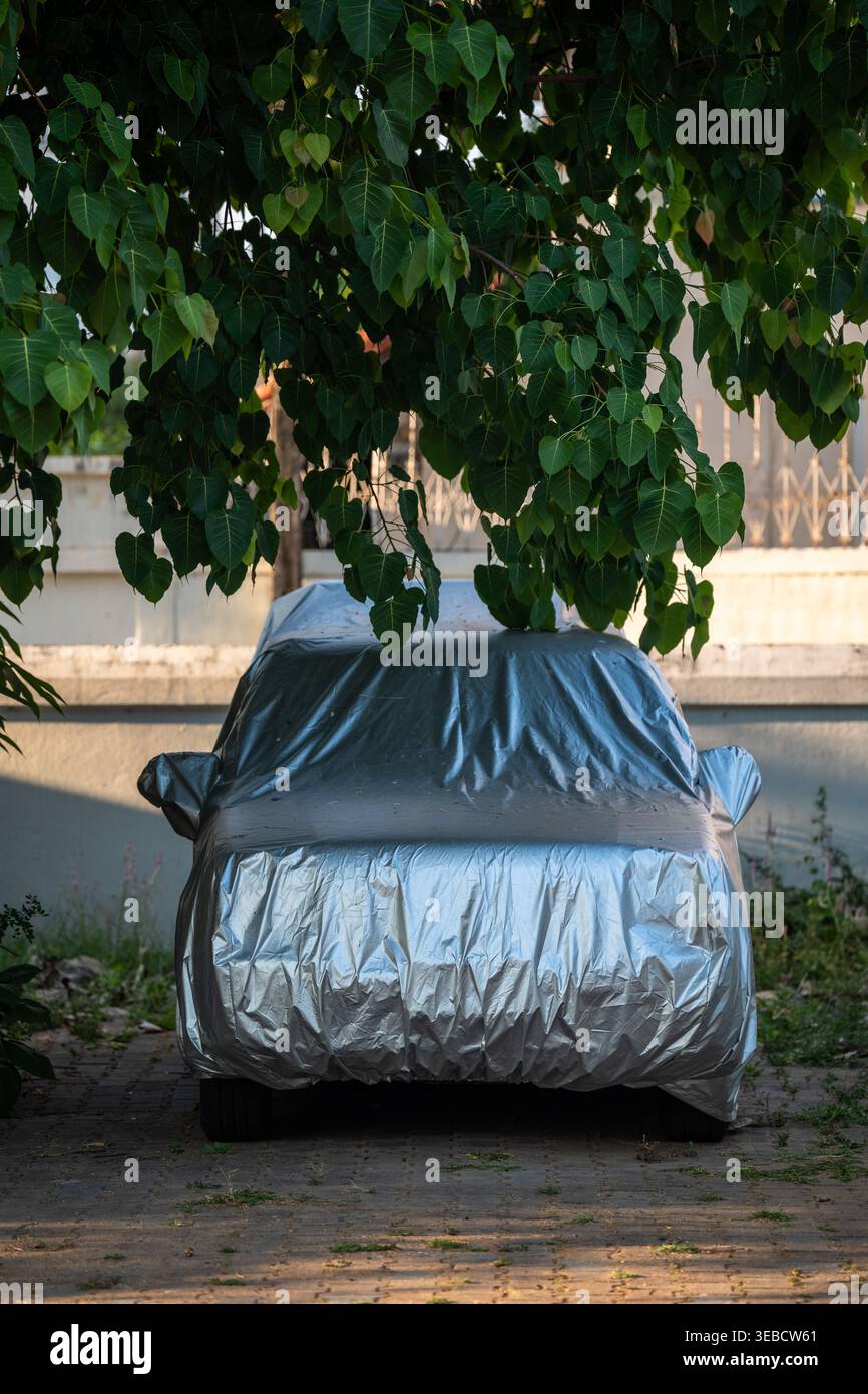 Das Auto ist mit Sonnenschutz und Heizung bedeckt und parkt im Schatten unter Bäumen an heißen Sommertagen in der Stadt. Stockfoto