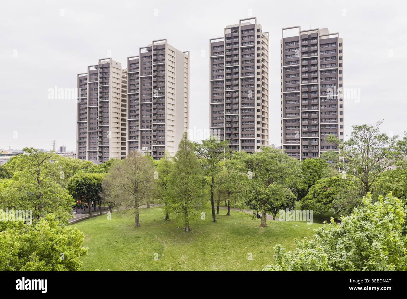 Blick aus der Vogelperspektive auf die hohen Wohnhäuser mit Blick auf einen üppig grünen Park mit verschiedenen Bäumen unter einem bewölkten Himmel Taiwan. Stockfoto
