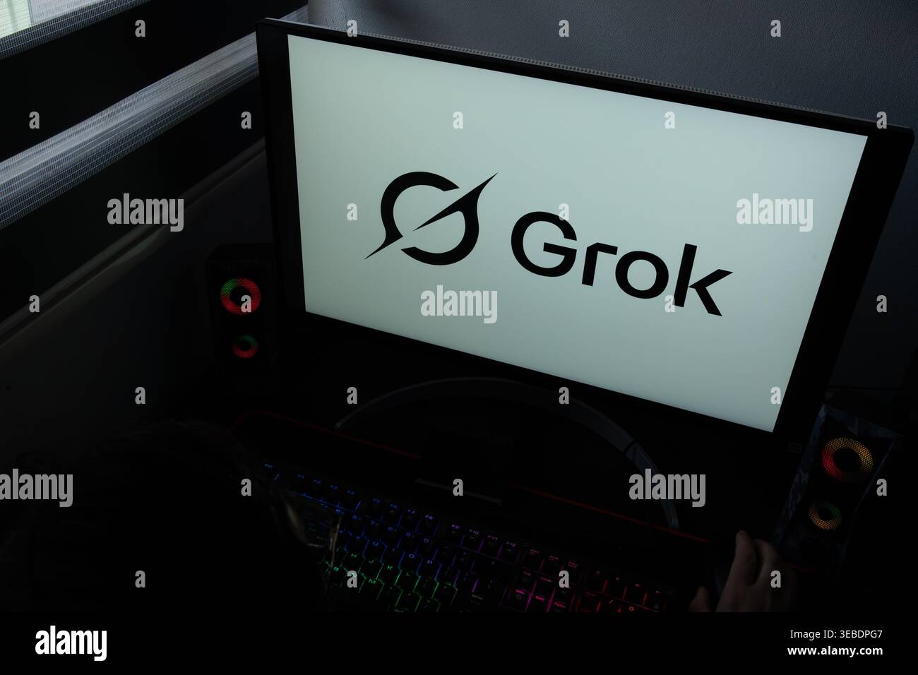 Das von XAI entwickelte Grok AI-Logo wird auf einem Computermonitor in einem dunklen Heimbüro angezeigt Stockfoto
