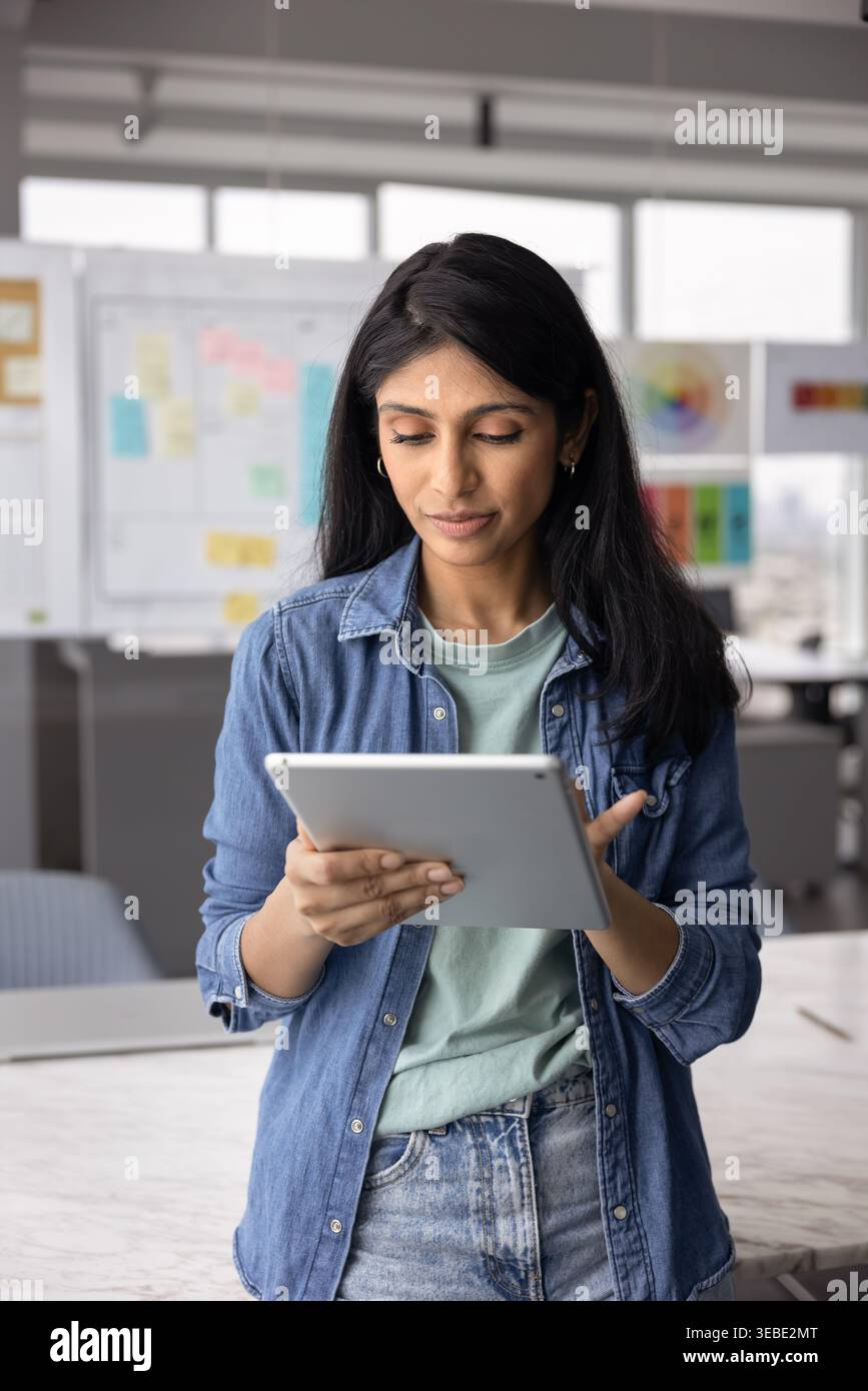 Eine hübsche indische Profi-Frau, die an einem Tablet arbeitet Stockfoto