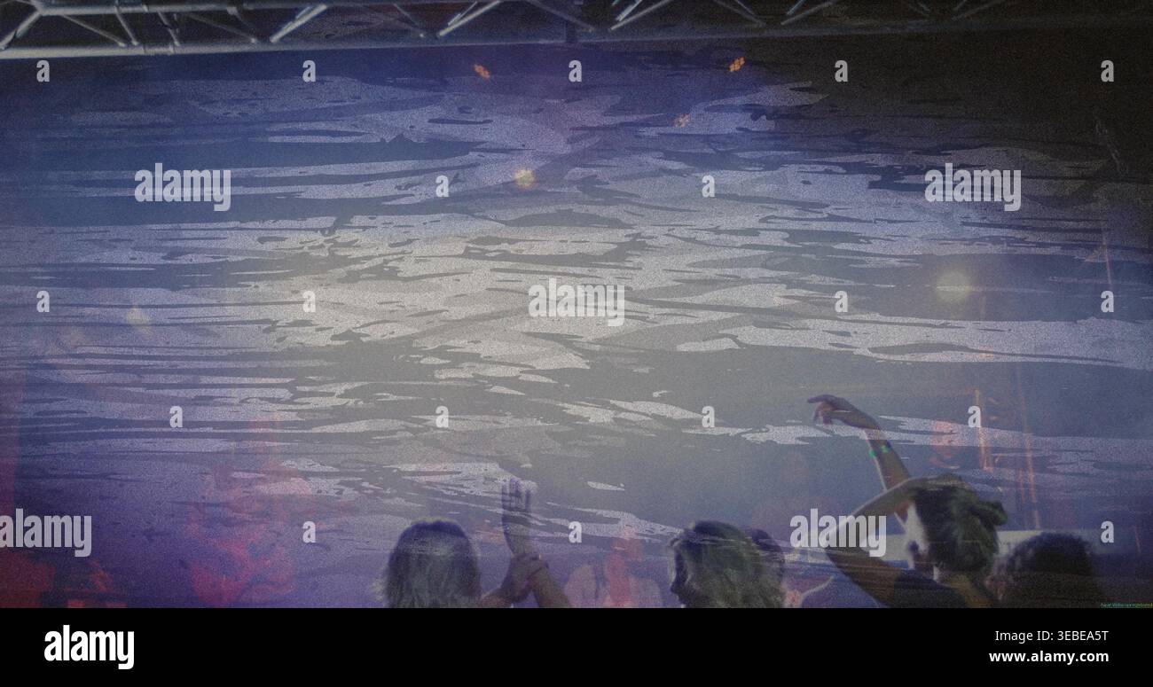 Eine kleine Gruppe von Fans, die in lässiger Kleidung im Club tanzen, mit LED-Hintergrund und Armbändern Stockfoto
