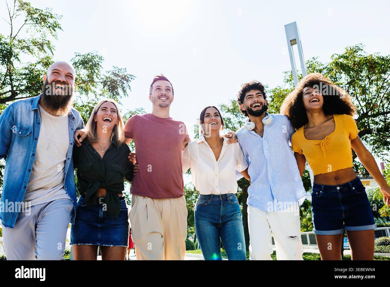 Multirassische Gruppe junger Freunde, die draußen spazieren und lachen Stockfoto
