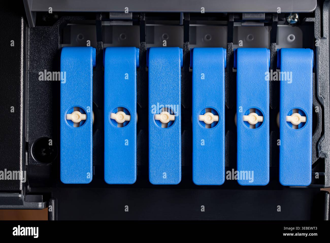 Nahaufnahme der blauen Tankdeckel im Fotodrucker. Makroansicht der Kappen des nachfüllbaren Tintentanks in einem professionellen Fotodrucker. Konzept des Contu Stockfoto