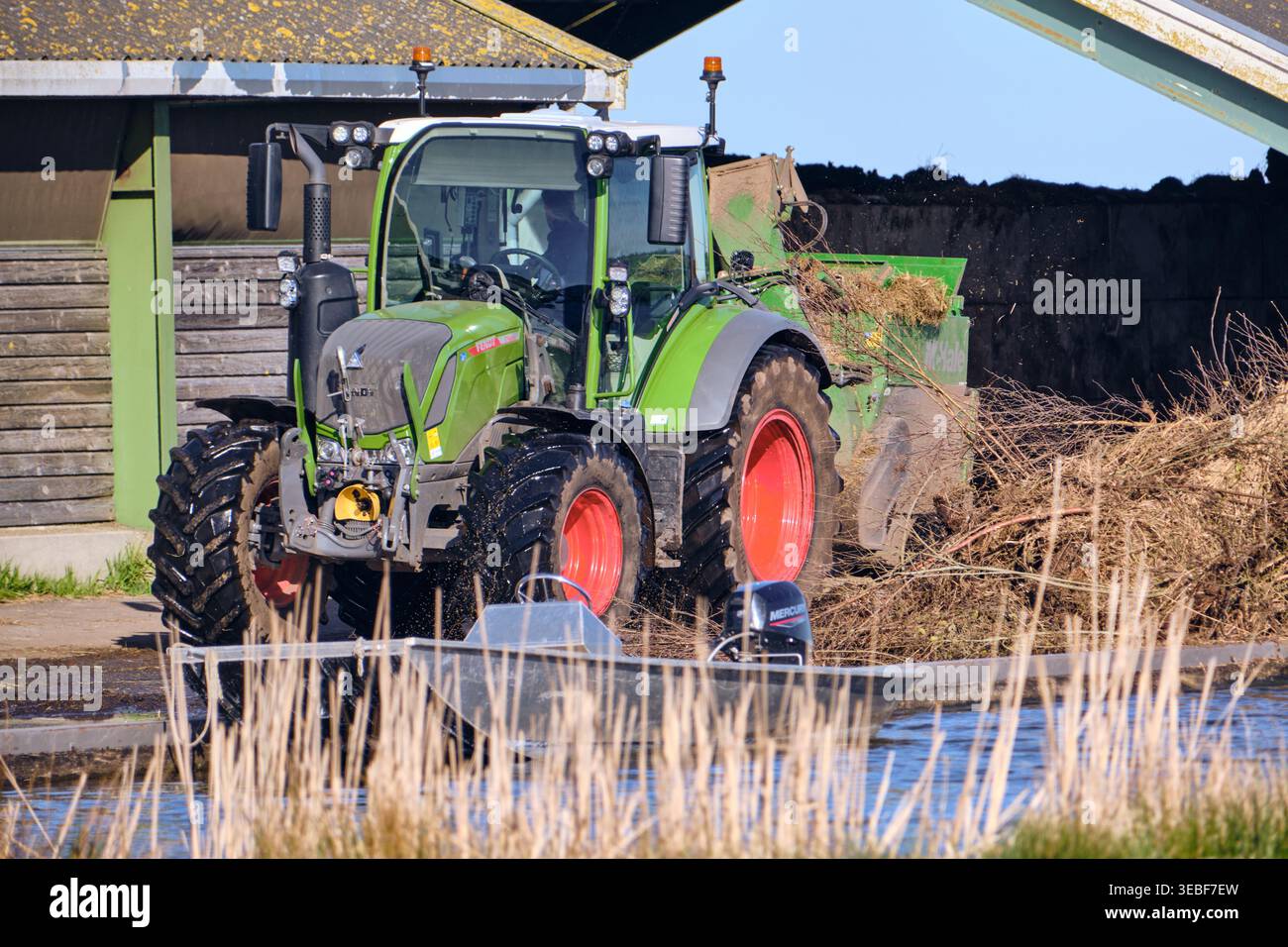 Landwirtschaftliche Effizienz: Umweltfreundlicher Traktor mit Anhänger, der organische Stoffe in das Wasser leitet, in den Niederlanden Stockfoto