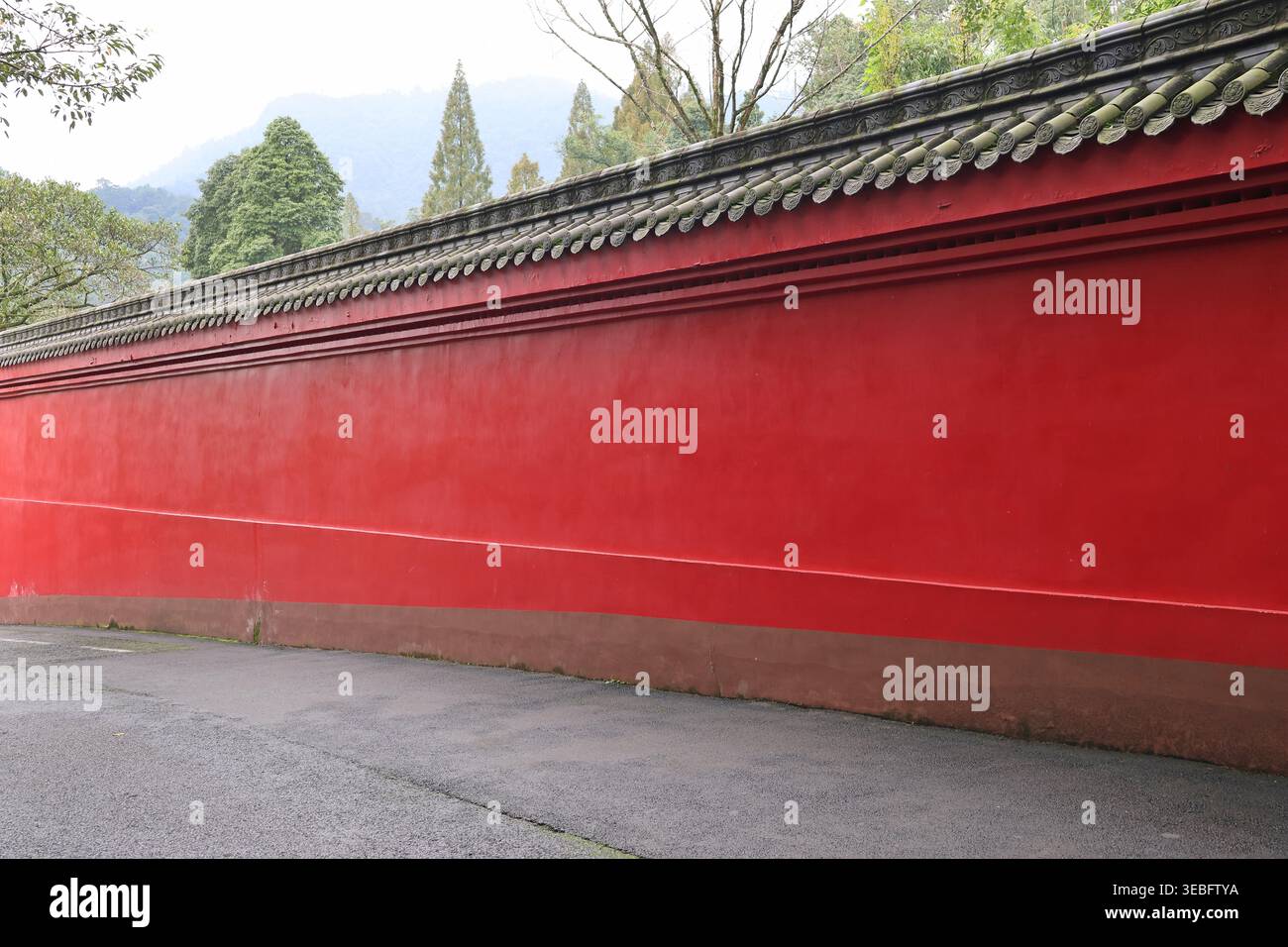 Alte Dachziegel der roten Wand sind mit dem Gesicht und Blumenmuster des Tieres in der Nähe des Baoguo-Tempels auf dem Berg Emei in Emeishan City gemeißelt Stockfoto