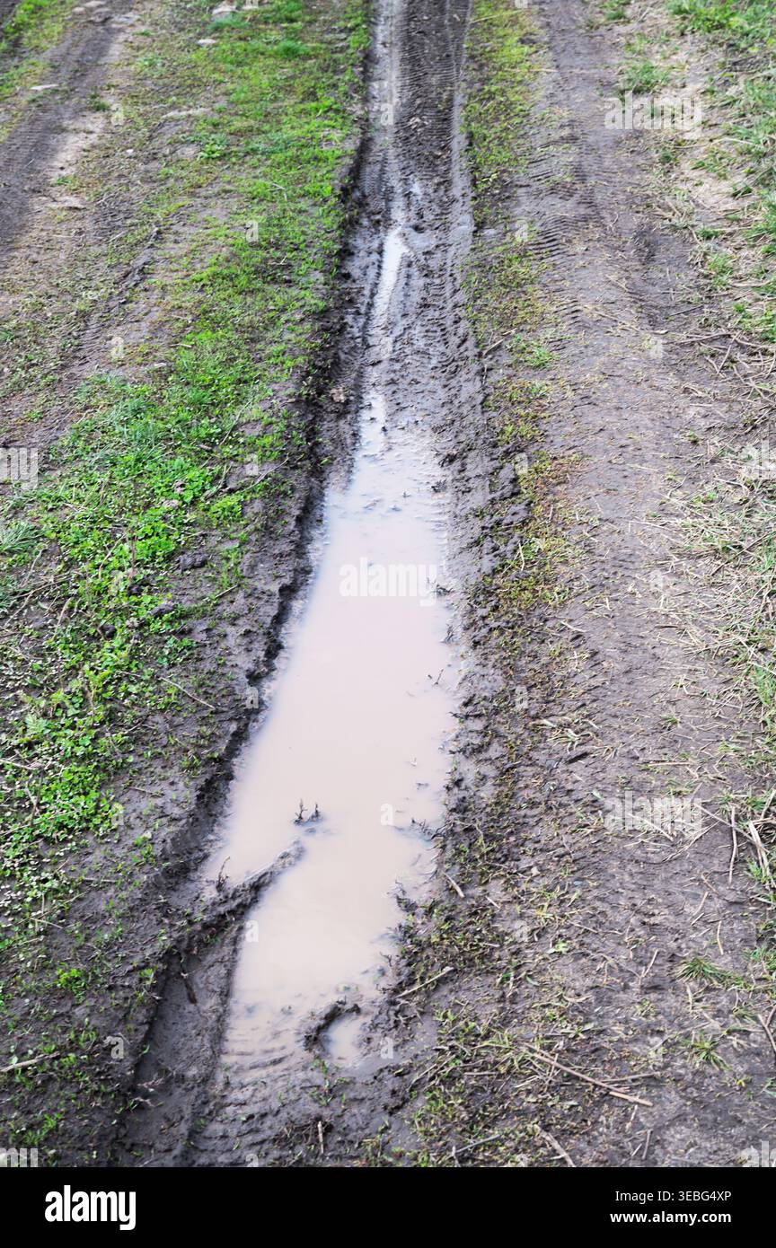 Tiefe, schlammige Reifenspuren, gefüllt mit Regenwasser im Freien Stockfoto