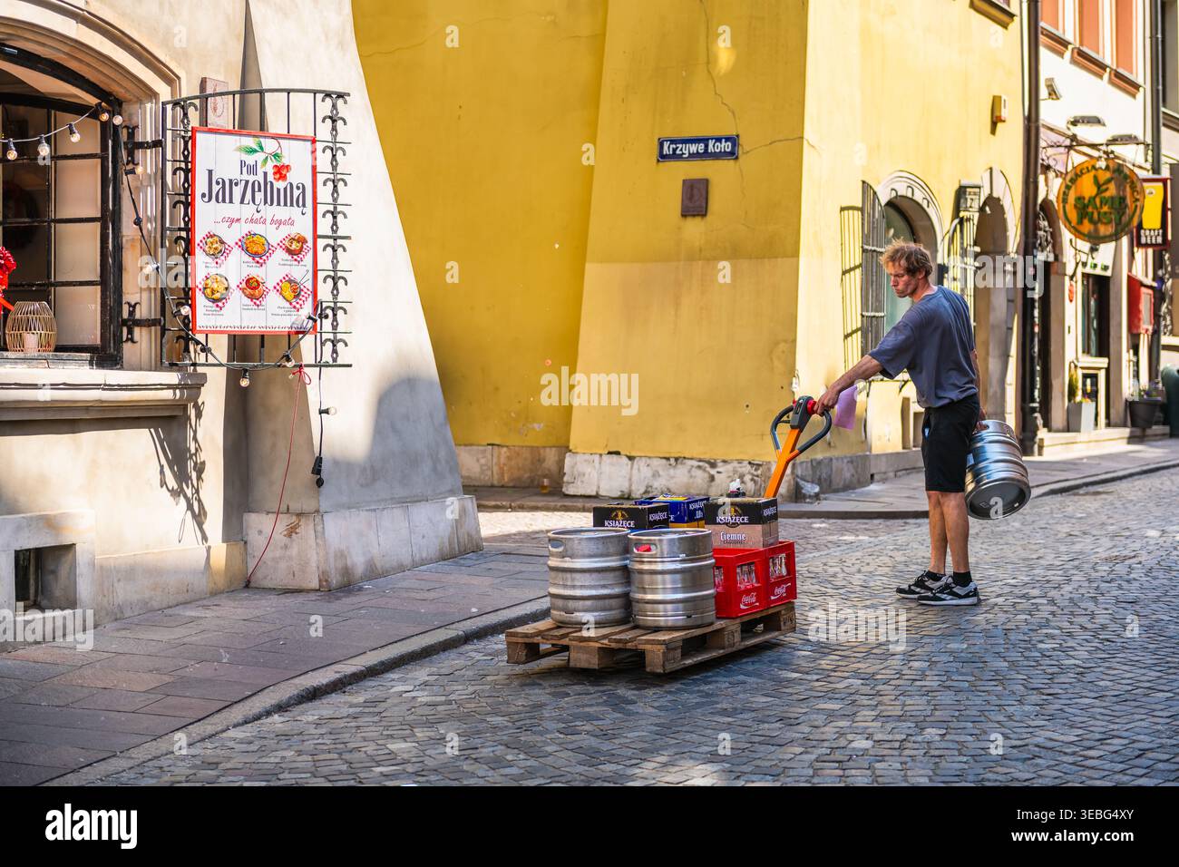 Warschau, Polen - 23. April 2025: Mann Einzelhandelsarbeiter mit Bierfass und leerer Flaschenkiste beim polnischen Pierogi-Restaurant auf dem Altstadtmarkt Stockfoto