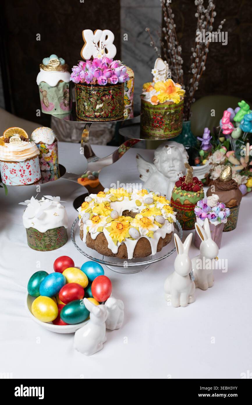 Festliches Osterstillleben mit Kuchen, hellen Eiern und Porzellanhasen. Stockfoto