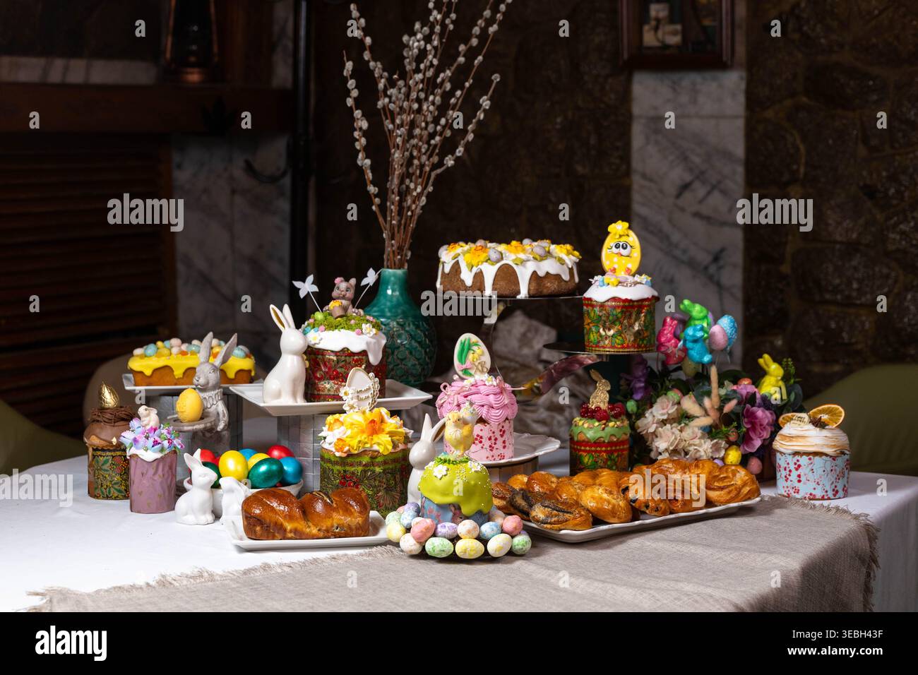 Festlicher Ostertisch mit traditionellen Kuchen, gefärbten Eiern und dekorativen Häschen. Stockfoto