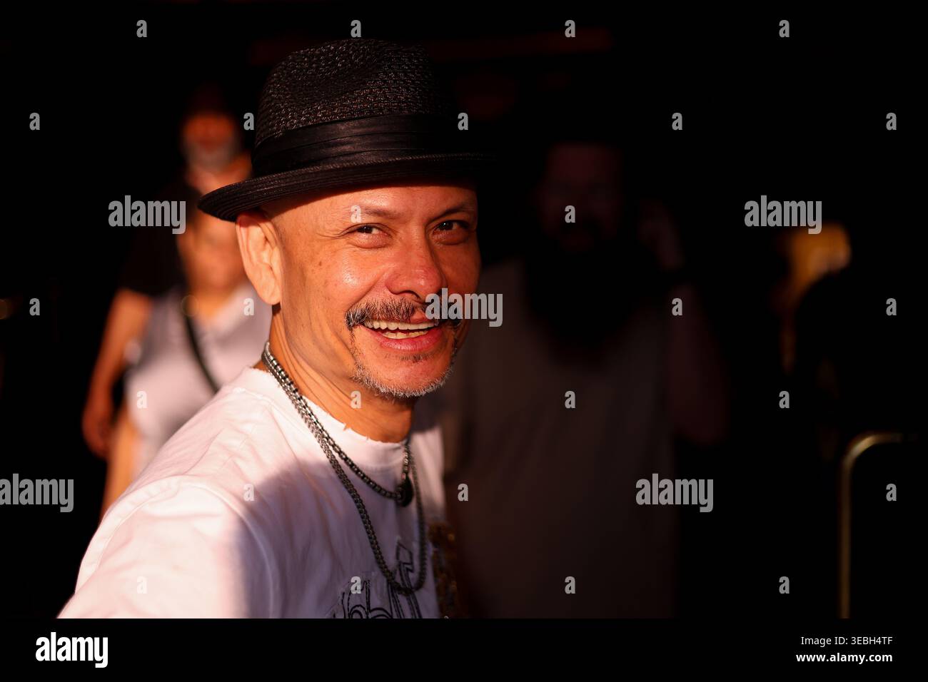 Hispanischer Mann mittleren Alters mit dunklem Fedora Hut und weißem T-Shirt auf dem Las Vegas Strip am 20. April 2026 Las Vegas, Nevada Stockfoto