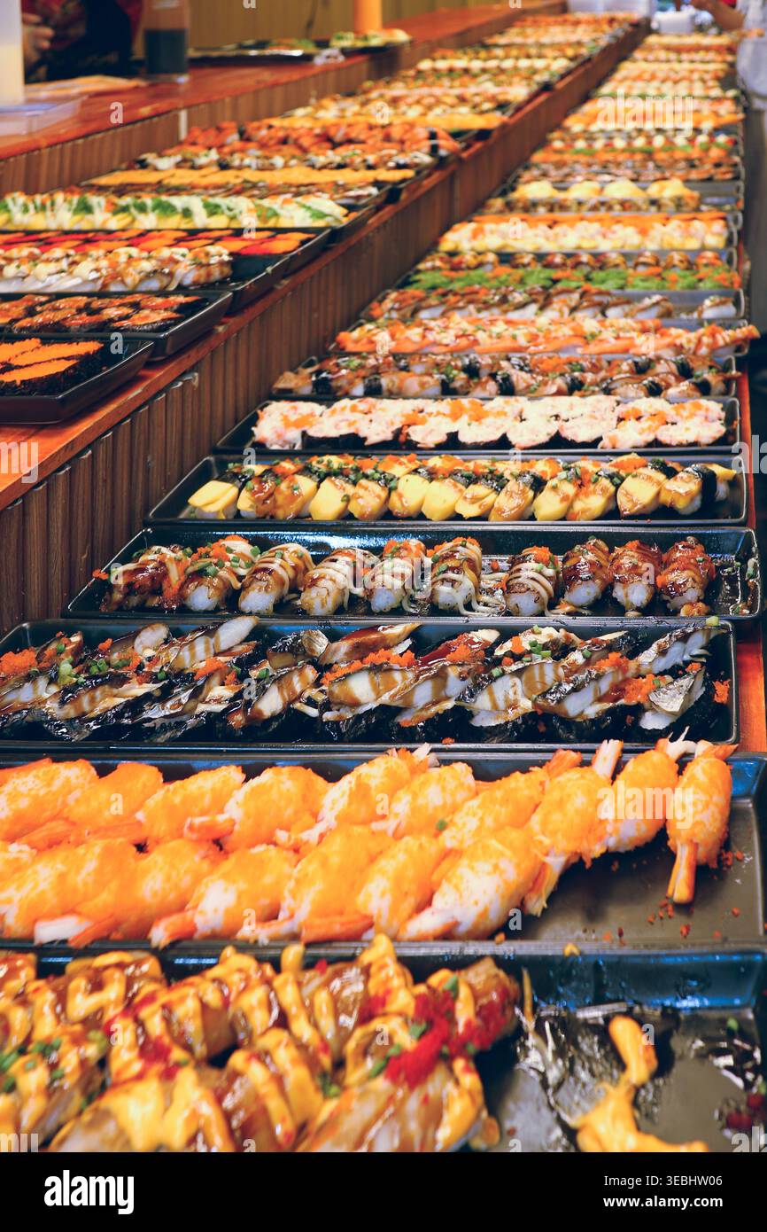 Dokumentarfilm Weitwinkel einer Sushi-Ausstellung auf einem geschäftigen thailändischen Markt. Die authentische Fusionskultur und das Catering lokaler Kleinunternehmen. Stockfoto