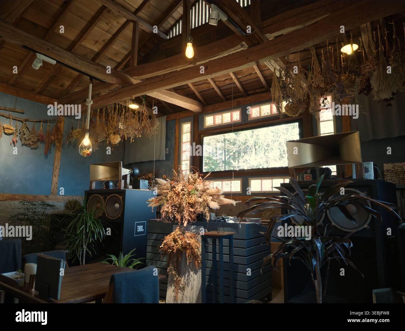 NASU, JAPAN - 12. April 2026: Innenraum eines rustikalen Cafés mit Vintage-Hornlautsprechern, getrockneten Blumenarrangements und Holzbalken. Stockfoto