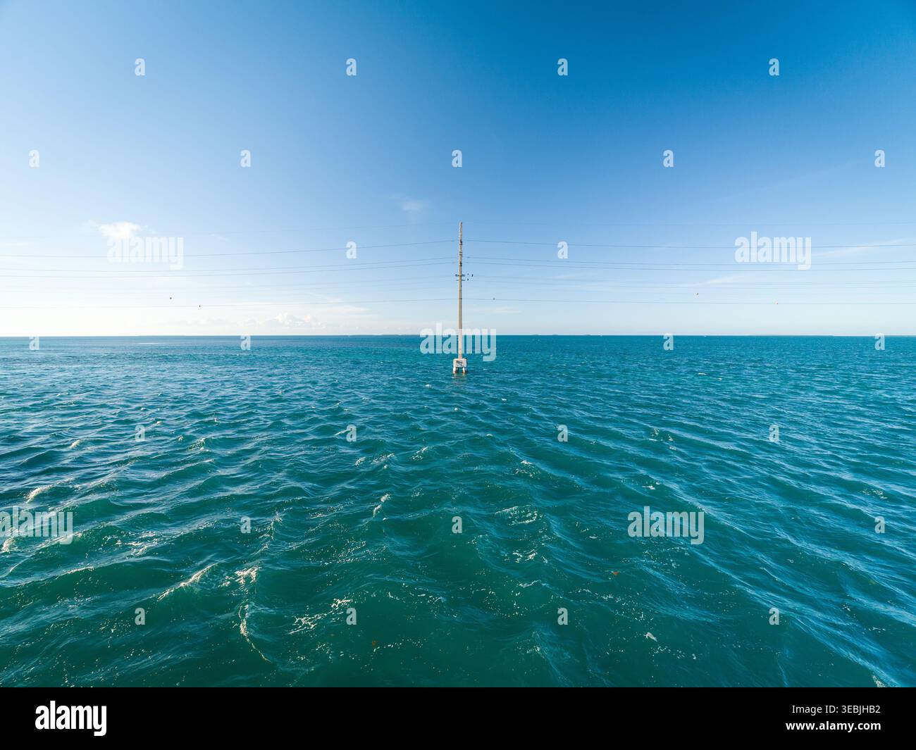 Ein einziger Industriepolster führt elektrische Kabel über das offene Meer unter klarem Himmel auf den Florida Keys Islands, USA. Stockfoto