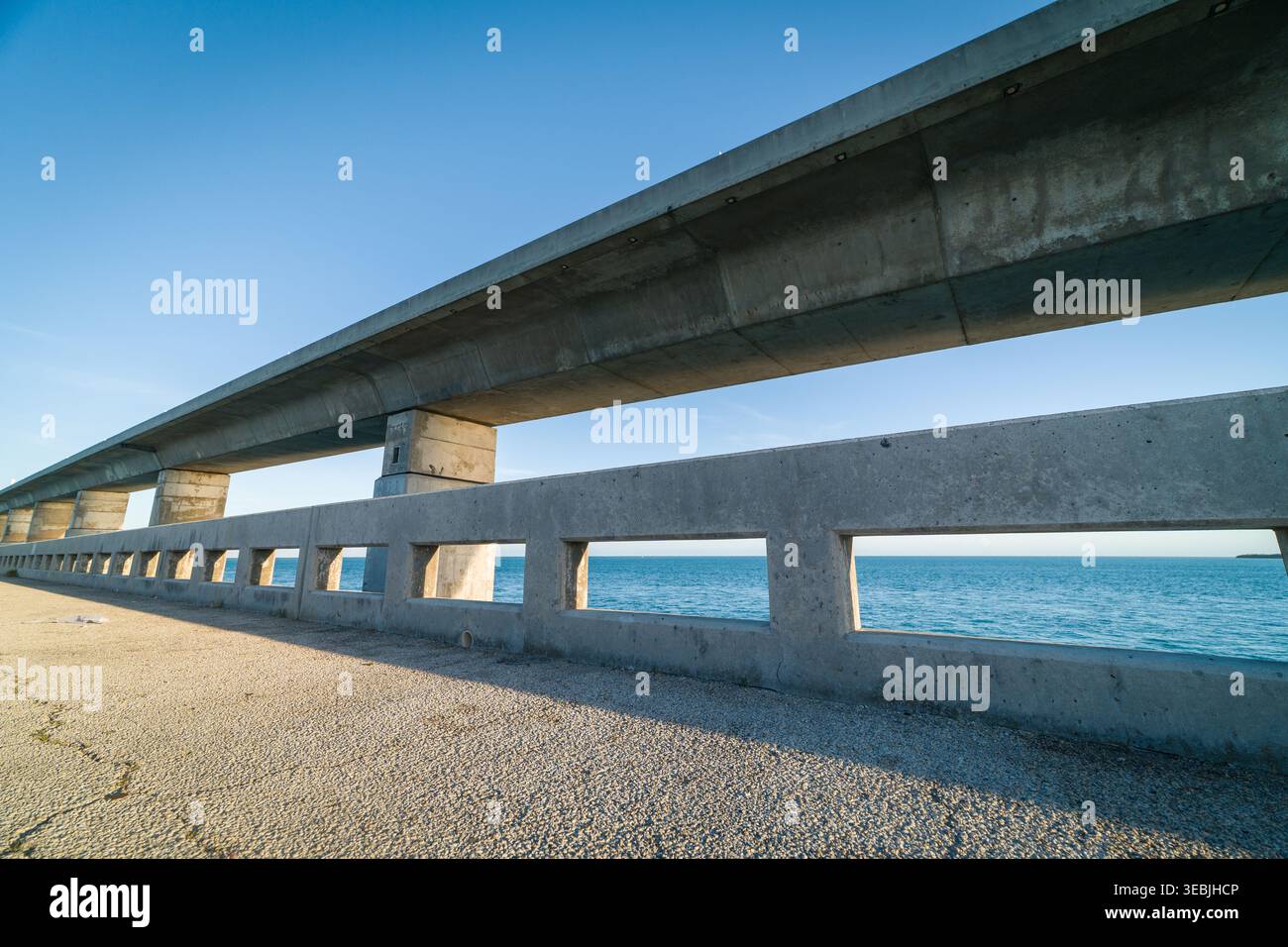 Eine massive Betonbrücke mit schweren Säulen überquert das hellblaue Meereswasser entlang des berühmten Overseas Highway in den Florida Keys. Stockfoto