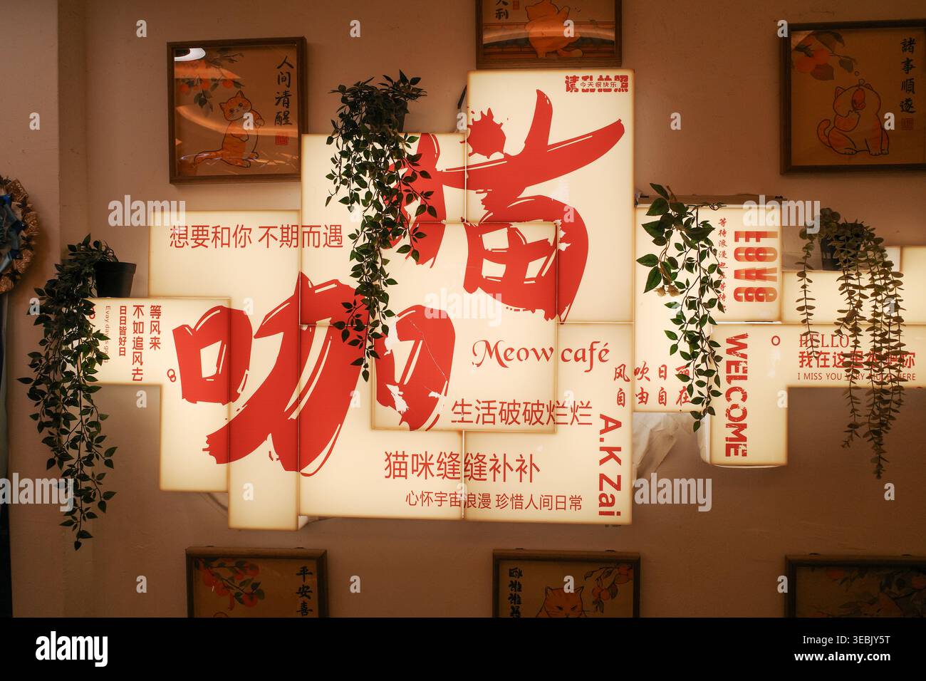 Warmer Innenraum mit roten Kalligraphiesildern. Grüne Reben hängen zwischen beleuchteten Tafeln. Chinesische Schriftzeichen schmücken die Wandflächen. Sanfte Beleuchtung en Stockfoto