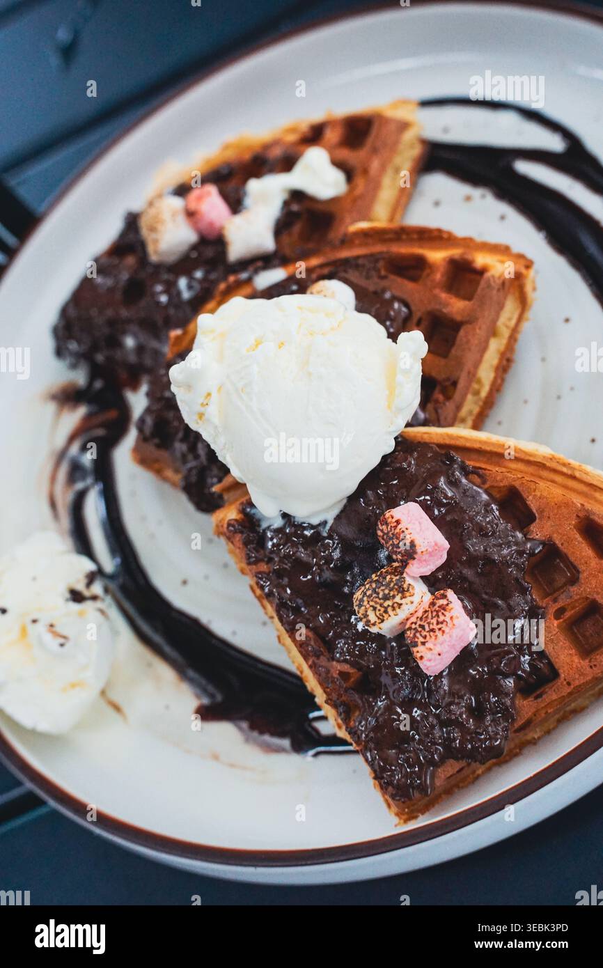 Schokoladenwaffel-Dessert mit Marshmallows, Eis und Schlagsahne auf Teller. Stockfoto