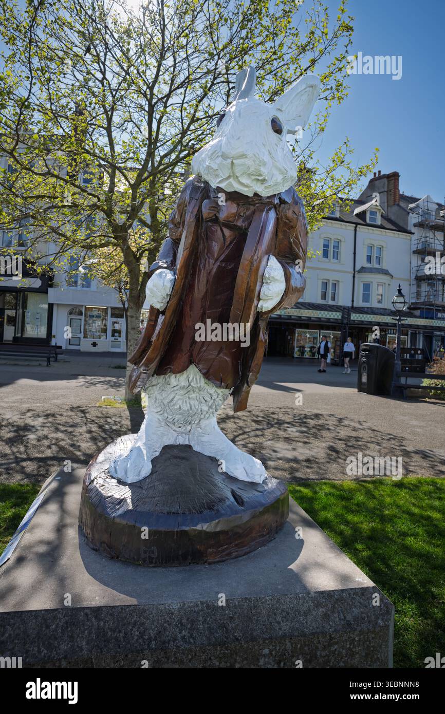 Hoch im Herzen von Llandudno, fängt die bezaubernde weiße Hasenstatue den Geist des Abenteuers ein. Sonniger Himmel und ein belebtes Backdro am Meer Stockfoto
