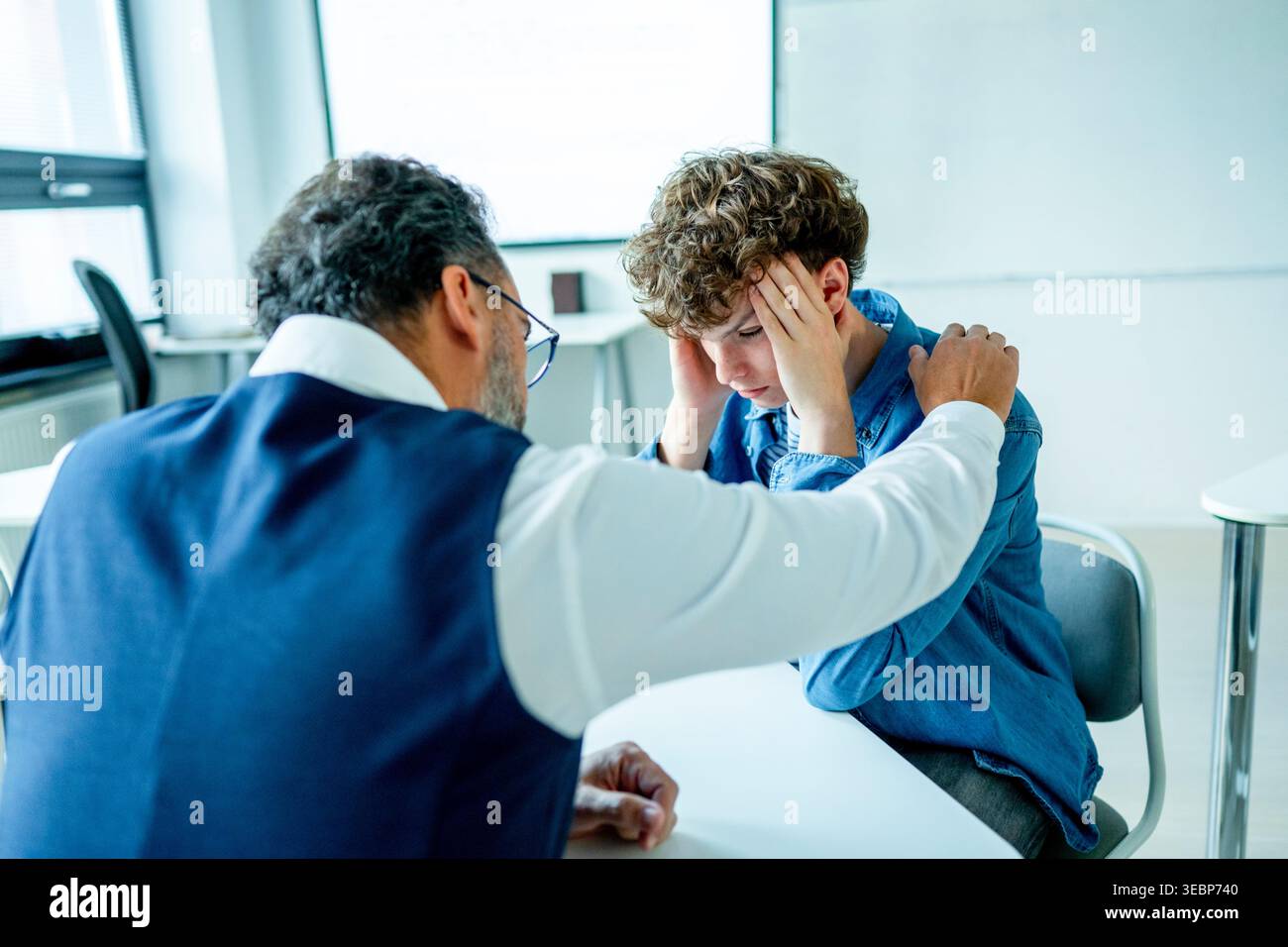 Lehrer, der sich um einen schwer wiegenden Schüler kümmert. Junge, der sich einem Lehrer anvertraut. Stockfoto
