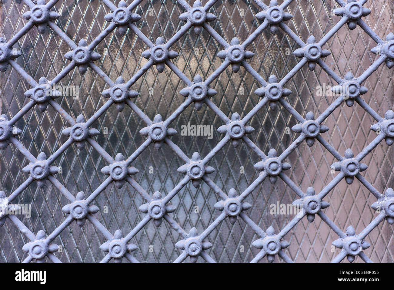 Nahaufnahme eines dekorativen Kühlergrills aus Schmiedeeisen mit geometrischem Gittermuster und floralen Details. Abstrakter Hintergrund mit Metallstruktur für Design. Stockfoto