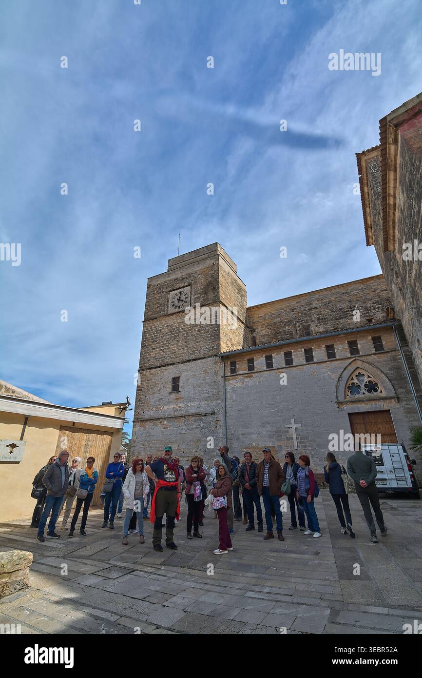 Mallorca Spanien - 27. April 2026: Eine Gruppe von Touristen trifft sich auf dem sonnendurchfluteten platz der Kirche Sant Jaume in Alcudia, um mehr über die historische Stadt zu erfahren Stockfoto
