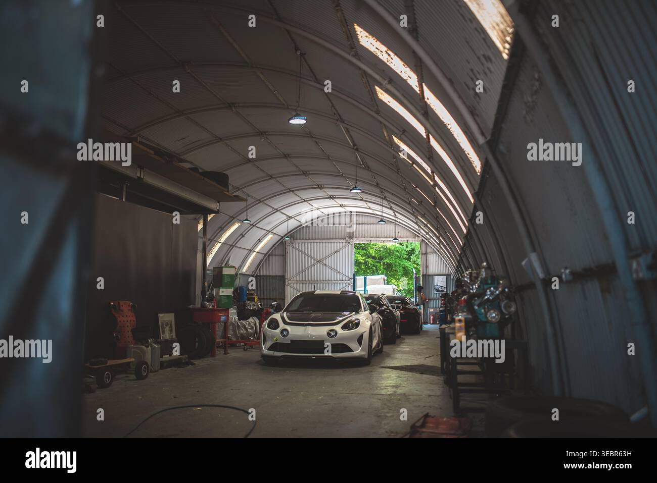 Der Oldtimer befindet sich in einer großen, offenen Garage mit einem Bogendach und Tageslicht Stockfoto