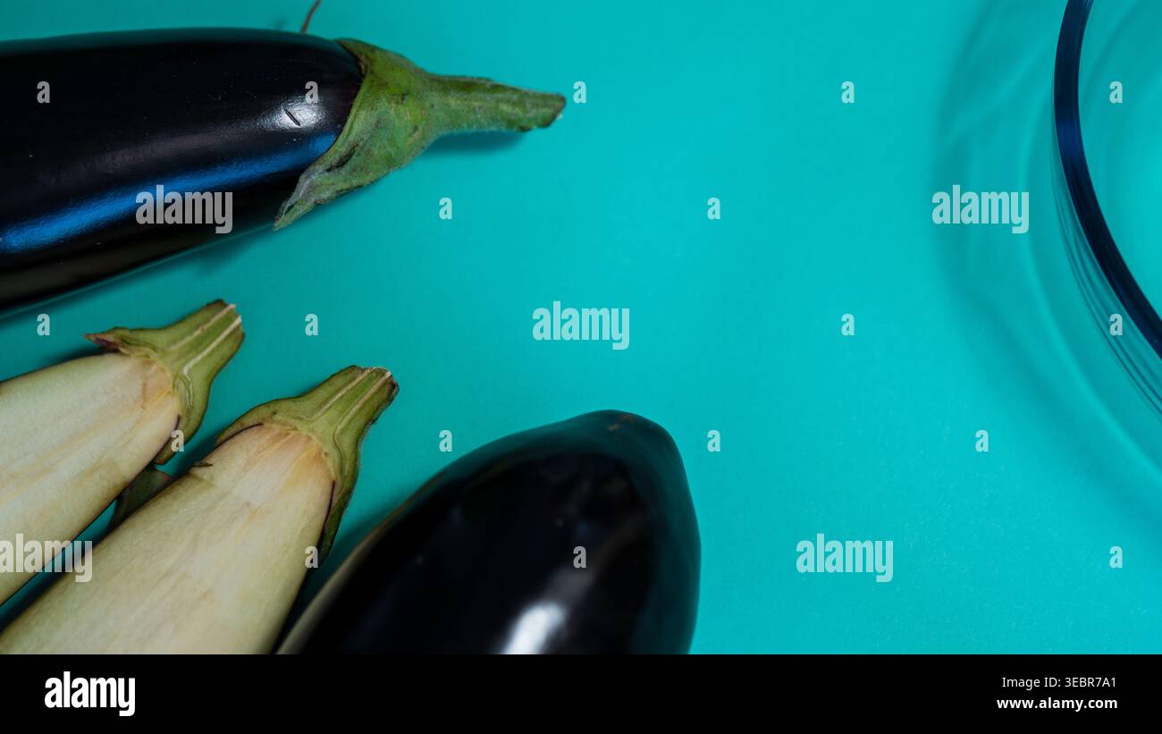 Ganze Auberginen und klare Glasschale auf blauem Hintergrund — Fresh Aubergine Flat Lay Food Photography Stockfoto