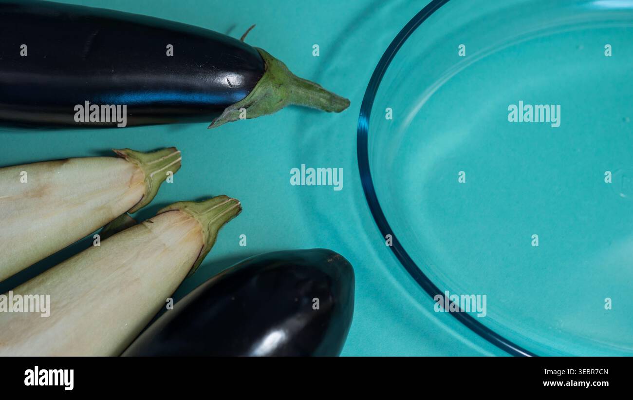 Ganze Auberginen und klare Glasschale auf blauem Hintergrund — Fresh Aubergine Flat Lay Food Photography Stockfoto