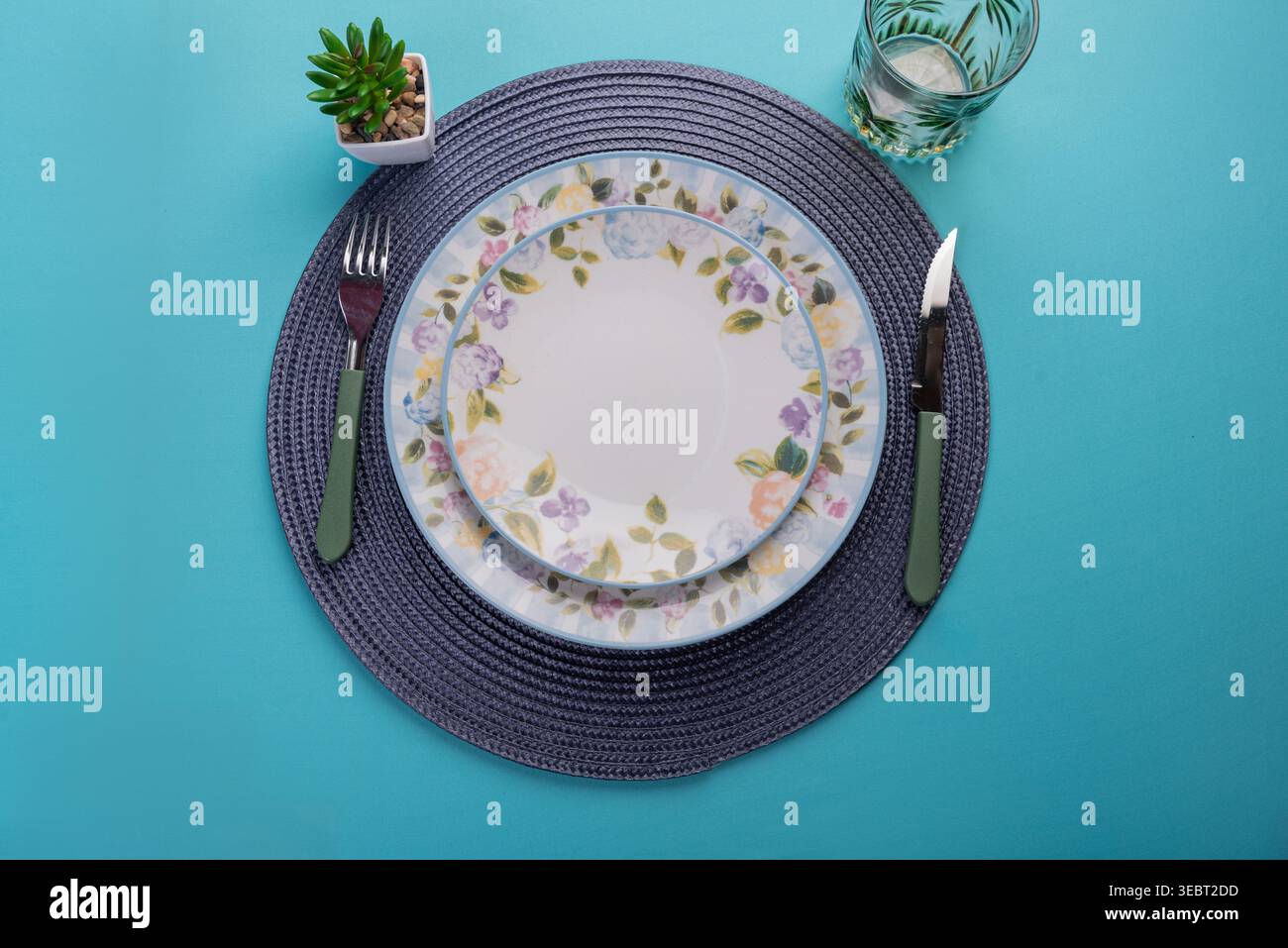 Blumenteller mit durchscheinendem Glas auf Blau. Weiche, diffuse Beleuchtung hebt Texturen hervor. Kopierbereich. Ideal für gesunde Ernährung, Wellness-Aktionen. Stockfoto