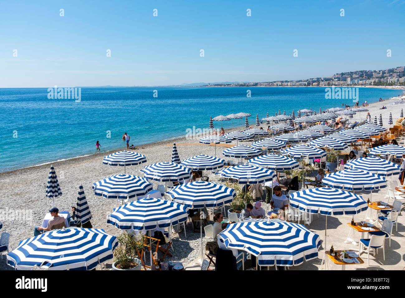 Frankreich, Nizza, Strandrestaurant mit blau-weiß gestreiften Sonnenschirmen. Stockfoto
