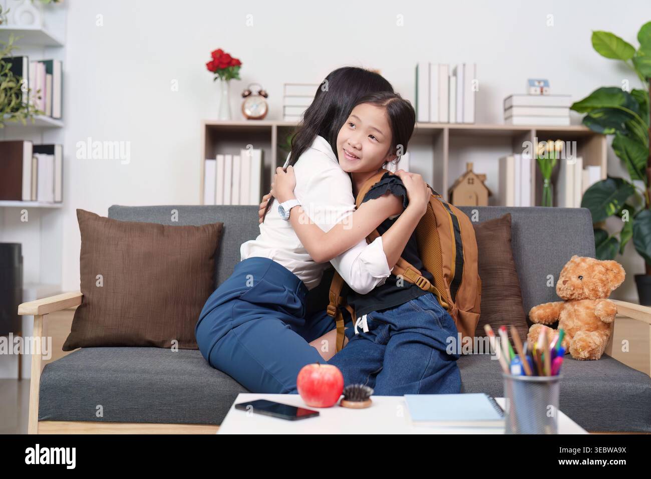 Asiatische Mutter und Tochter umarmen vor der Schule zu Hause Stockfoto