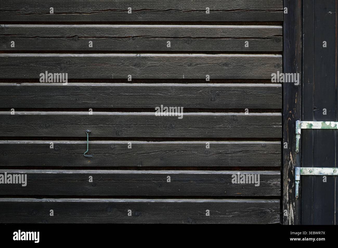 Verwitterte horizontale Holzdielen, die natürliche Alterung und die organische Struktur dunkler, abgenutzter Holzoberflächen zeigen. Stockfoto