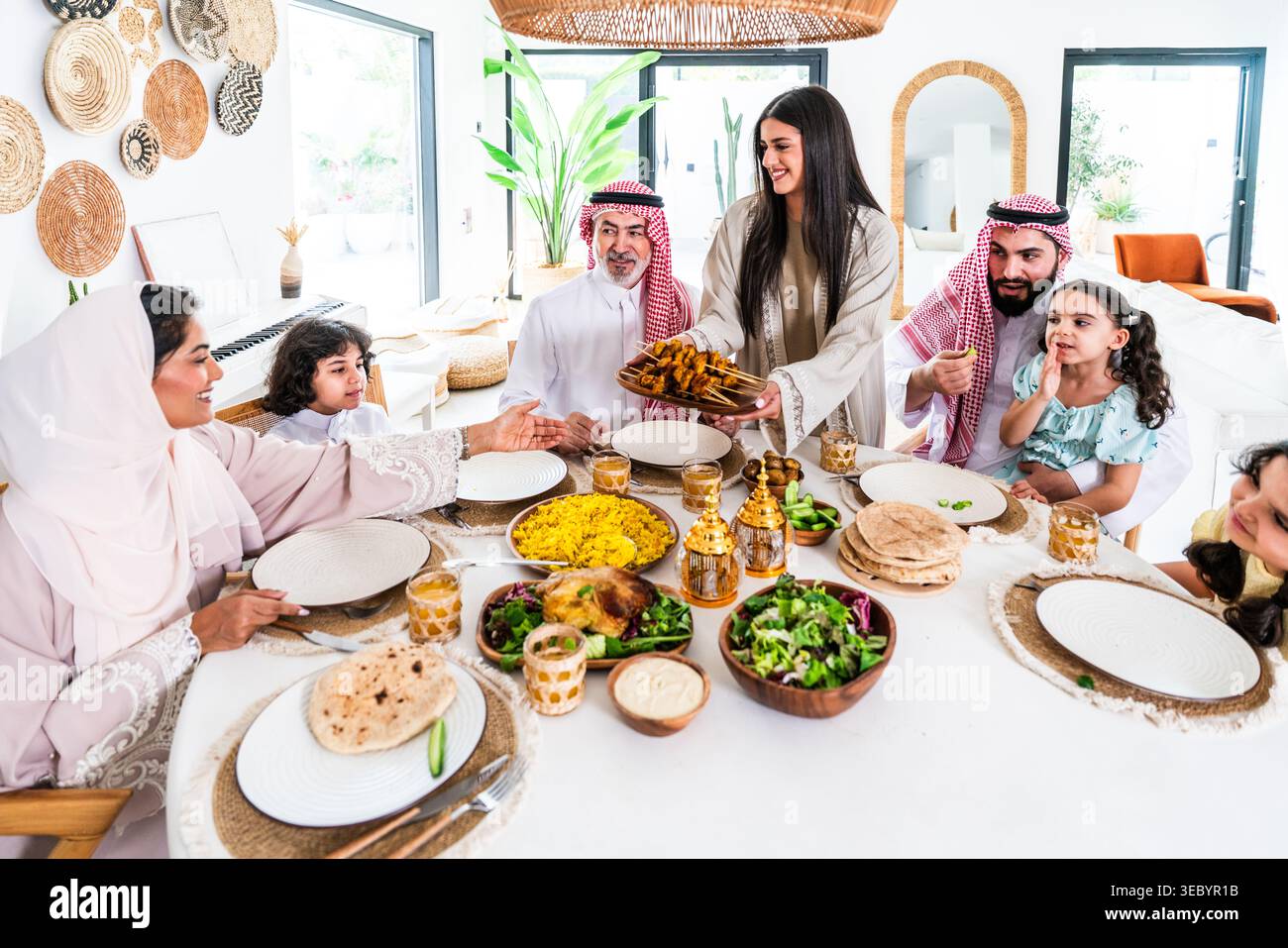 Familie aus dem Nahen Osten, die ein gemeinsames kulinarisches Erlebnis genießt, Eltern und Kinder sitzen an einem Tisch und feiern Freundschaft und Zweisamkeit während SHA Stockfoto