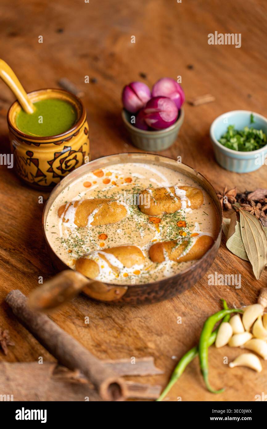 Eine komplette und ansprechende Präsentation eines köstlichen indischen vegetarischen Kofta-Currys in einer rustikalen Pfanne. Es wird elegant serviert mit frischen Gewürzen, Angebot Stockfoto
