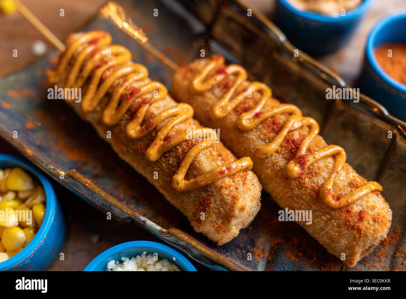 Diese ansprechende Nahaufnahme unterstreicht die verlockende knusprige Textur und den großzügigen Sauce-Nieseln auf zwei herzhaften Maishunden. Das perfekte klassische Komfortgericht, r Stockfoto