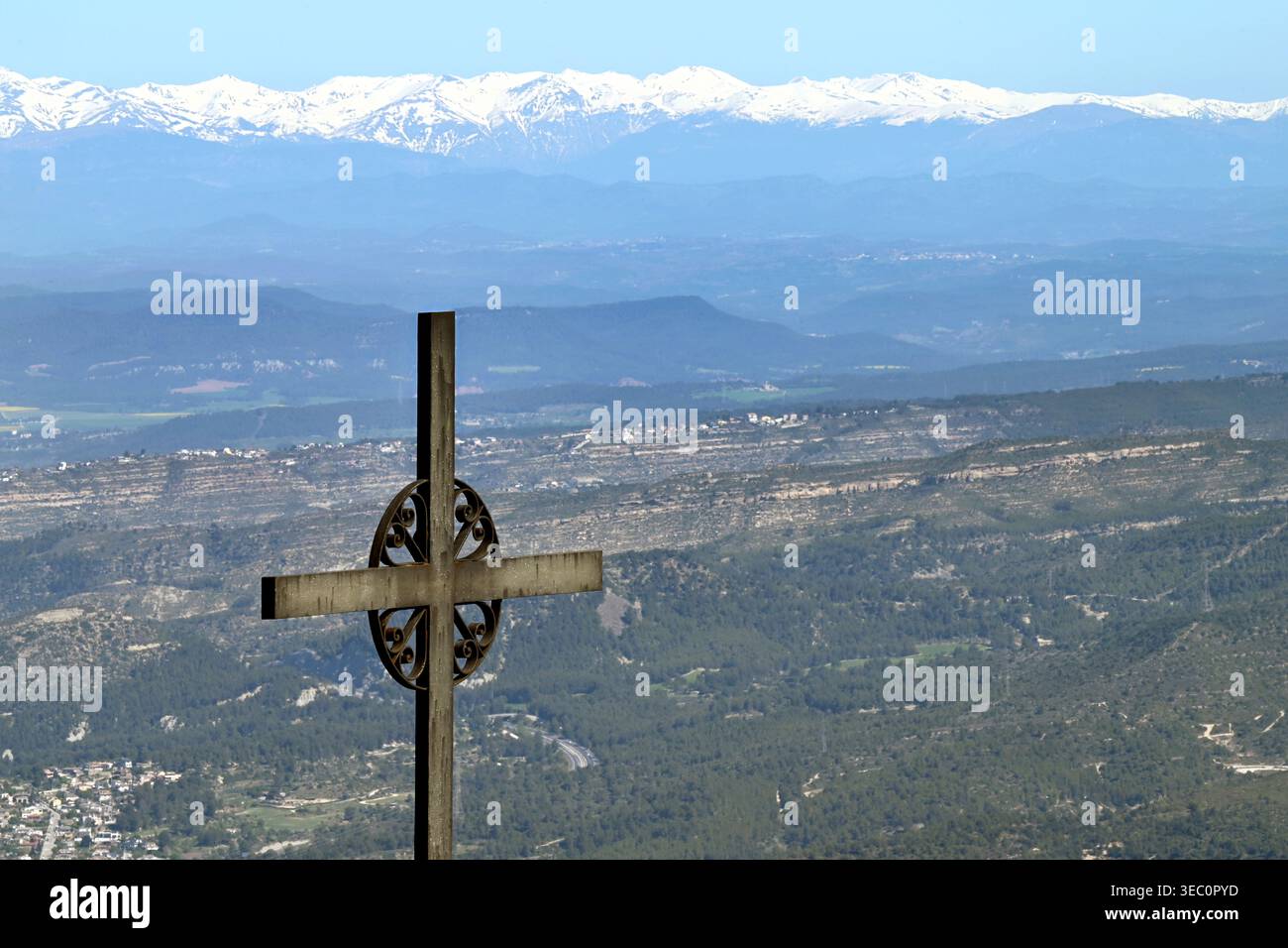 Eisernes Kreuz von Saint Michael (Creu de Sant Miquel) mit Blick auf die schneebedeckten Pyrenäen und die Tallandschaft unter blauem Himmel in Montserrat, Spanien Stockfoto