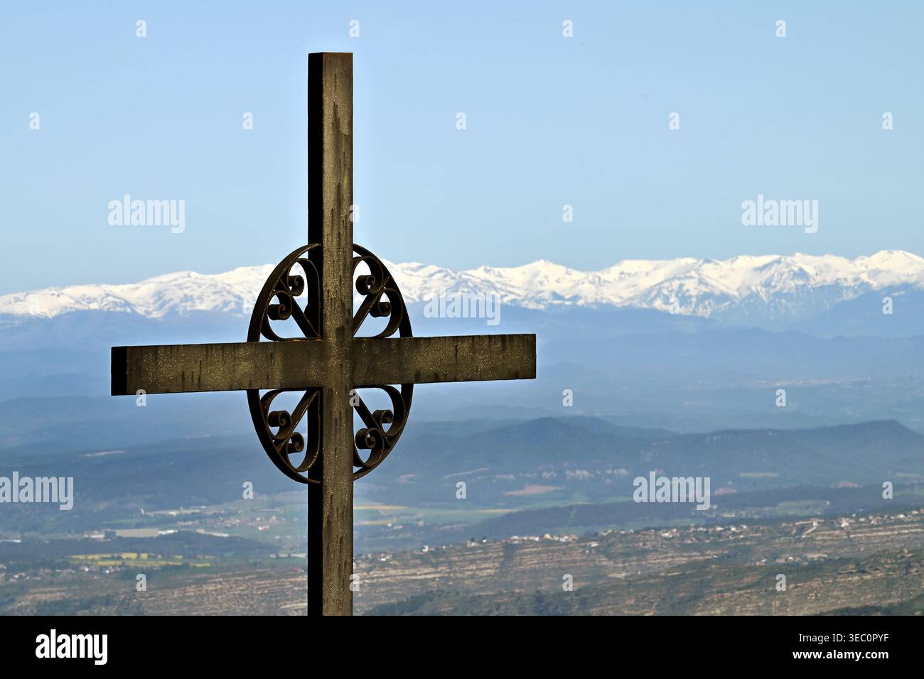 Eisernes Kreuz von Saint Michael (Creu de Sant Miquel) mit Blick auf die schneebedeckten Pyrenäen und die Tallandschaft unter blauem Himmel in Montserrat, Spanien Stockfoto