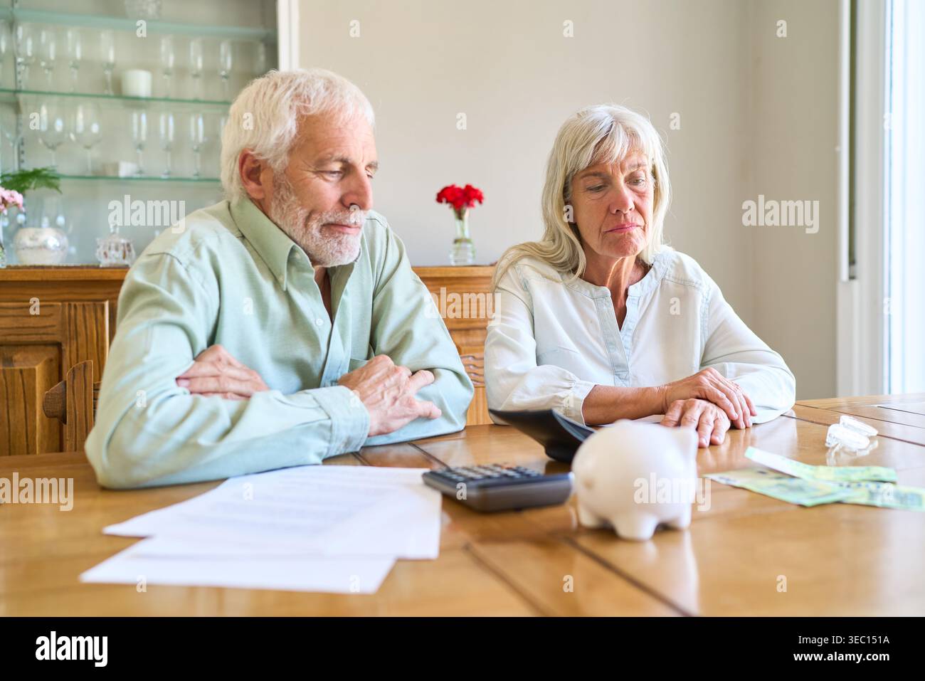 Herausforderungen bei der Altersvorsorge – ein älteres Ehepaar sitzt an einem Tisch und sieht besorgt aus, während es die Finanzdokumente überprüft. Stockfoto