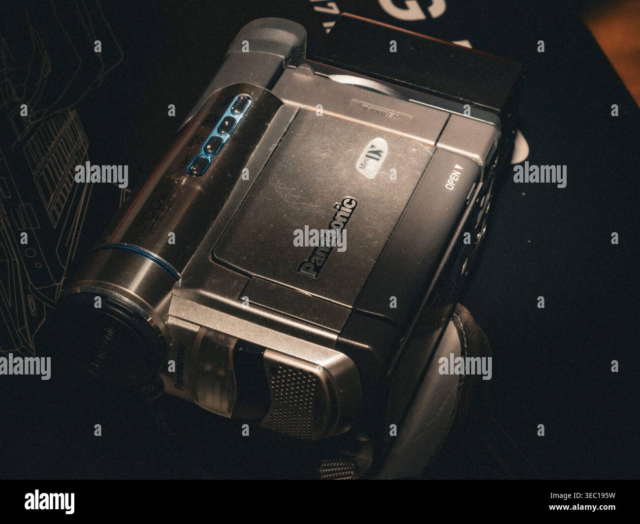 Panasonic MiniDV Camcorder im Vintage-Stil mit silbernem Gehäuse und digitalen Zoommarkierungen auf dunkler Oberfläche bei schlechten Lichtverhältnissen Stockfoto