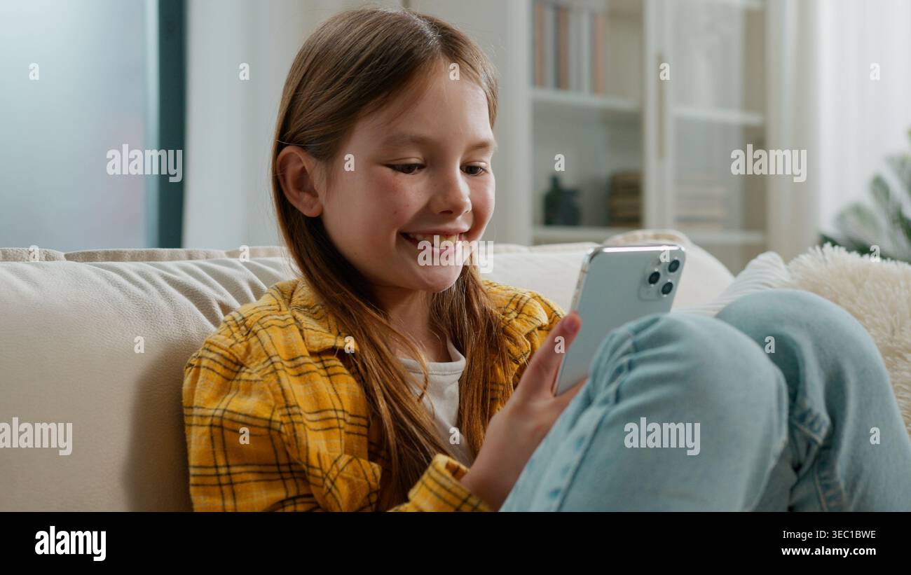Glückliches kaukasisches Mädchen, das in Handy schaut SMS Chats Nachrichten in sozialen Netzwerken lächelndes Kind Tochter früherer Benutzer mit Smartphone Stockfoto