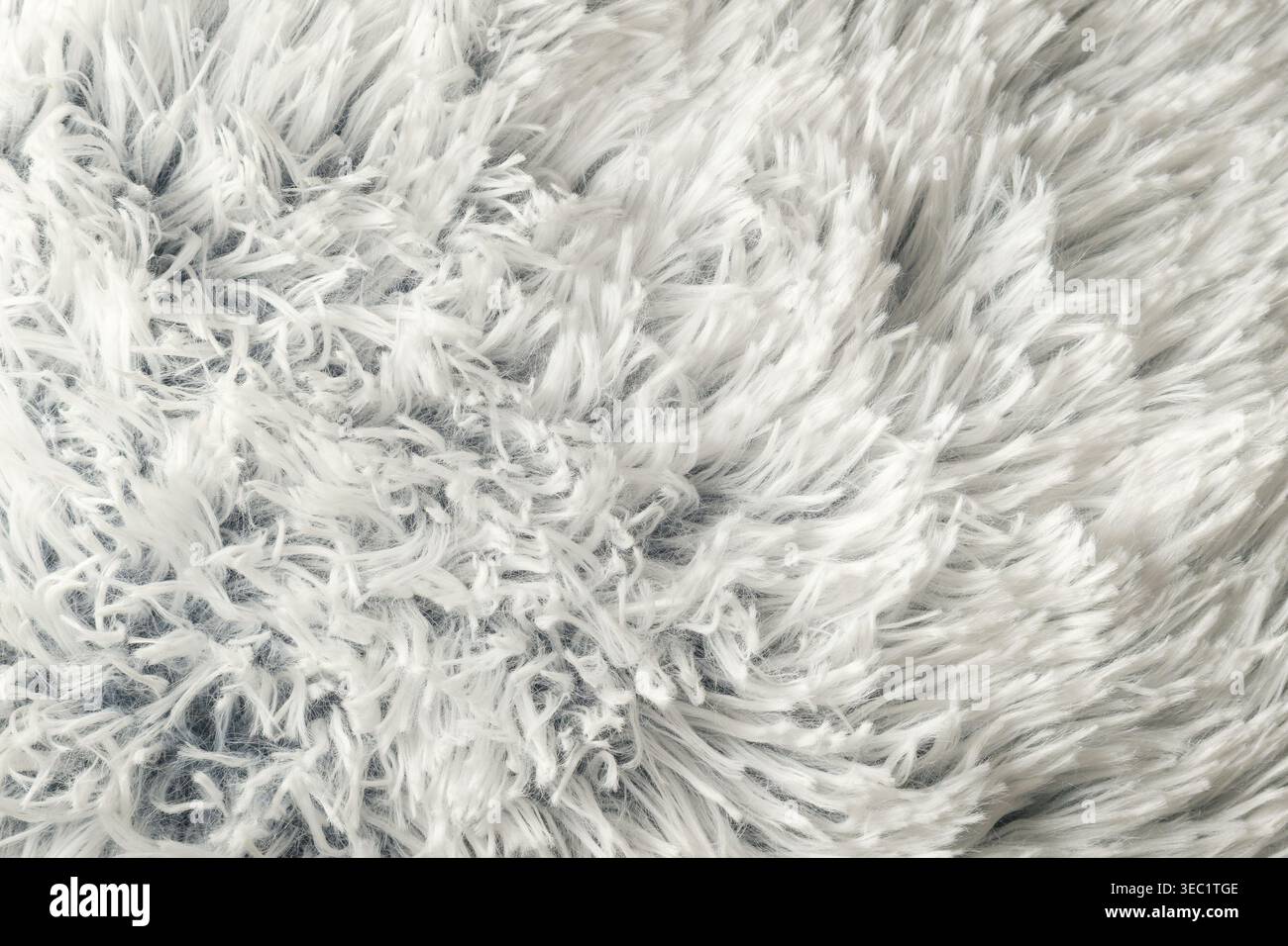 Weißer flauschiger Kunstfelltexturhintergrund, weicher zotteliger Teppich mit Textil-Detail Stockfoto