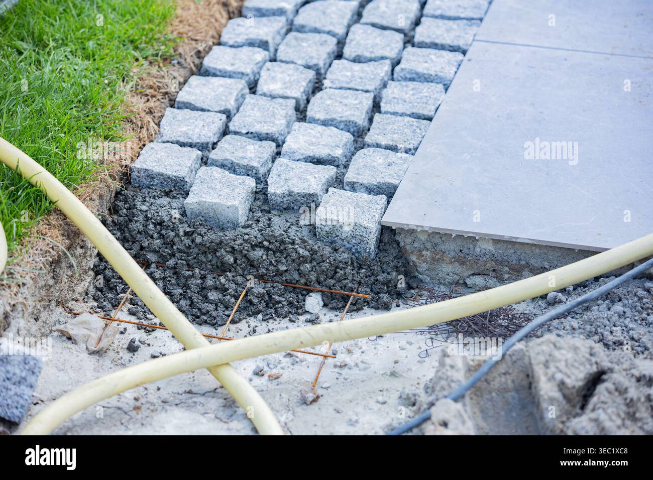Nahaufnahme der Pflastersteinbefestigung, die Granitblöcke auf einer vorbereiteten Basis zeigt und Bau- und Landschaftsarbeiten veranschaulicht i Stockfoto
