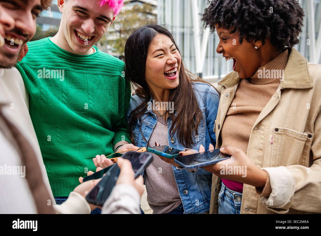 Multirassische Freunde, die Mobiltelefone benutzen und lachen Stockfoto