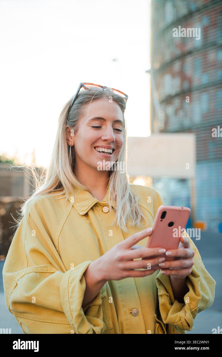 Happy Woman interagiert mit ihrem Smartphone und drückt Freude und Begeisterung aus, während sie sich online mit Freunden in einem fröhlichen Moment der Freizeit verbindet Stockfoto