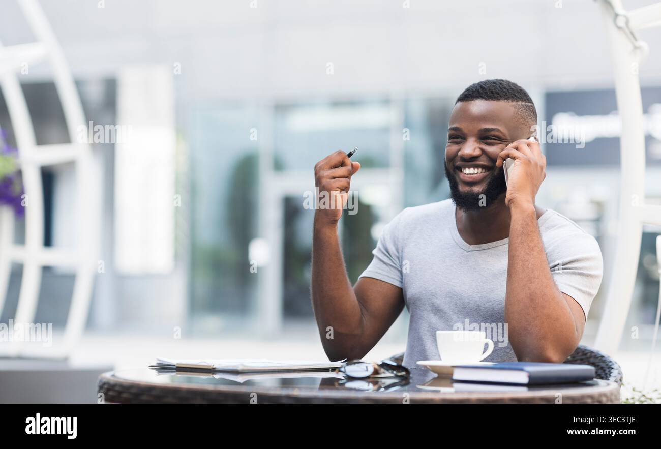 Mann genießt Unterhaltung, während er im Outdoor Cafe in der Nähe des modernen Gebäudes sitzt Stockfoto